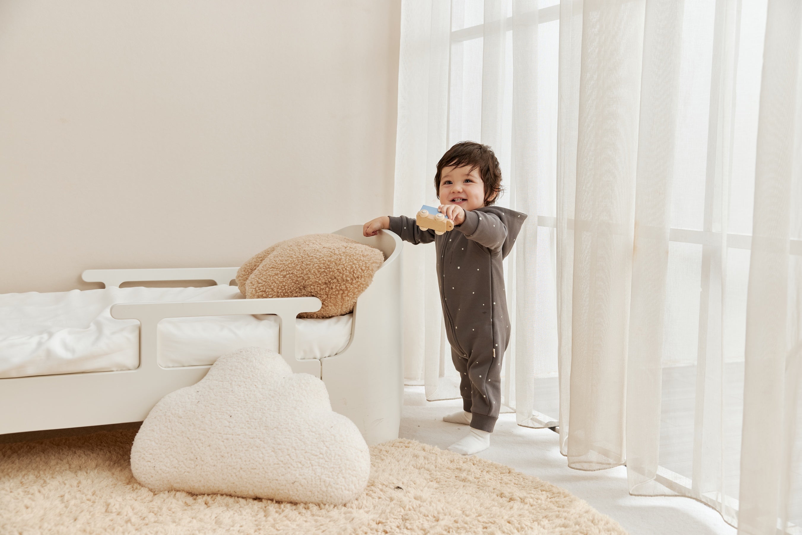 Child playing with a toy in a bright room with large windows