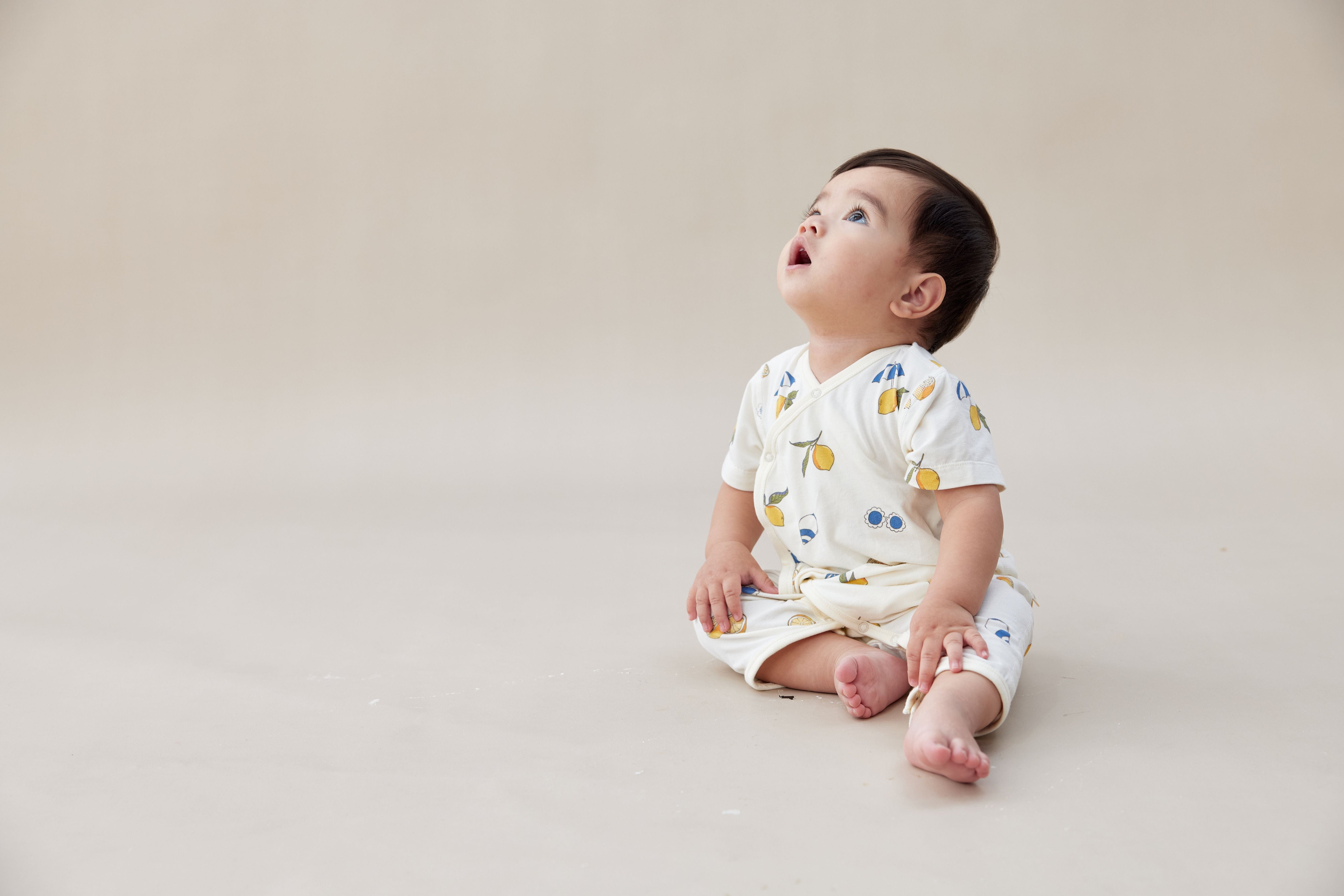 baby in lemon kimono sleeper watching the celling