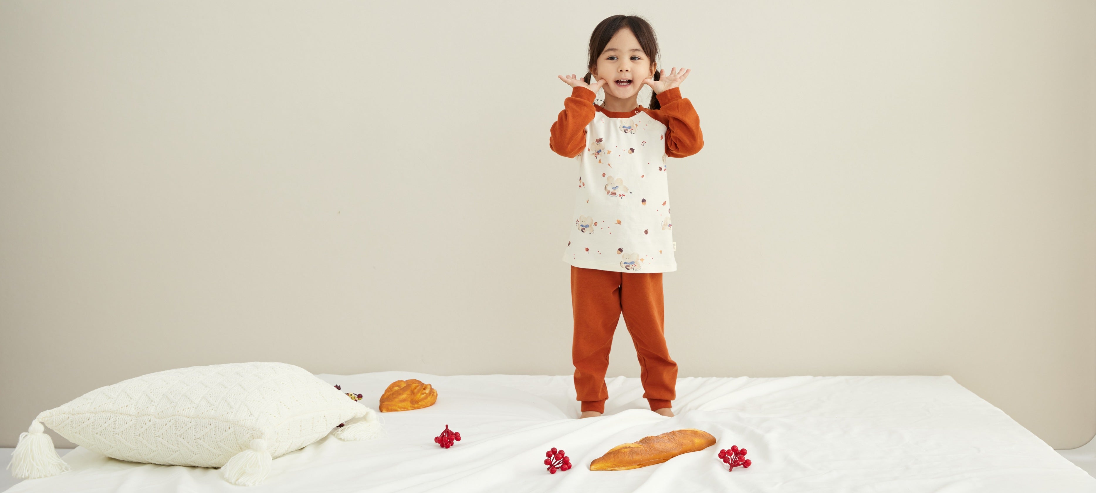 Super Cute girl wearing norsu organic's organic maple-leaf pajamas and standing on the bed