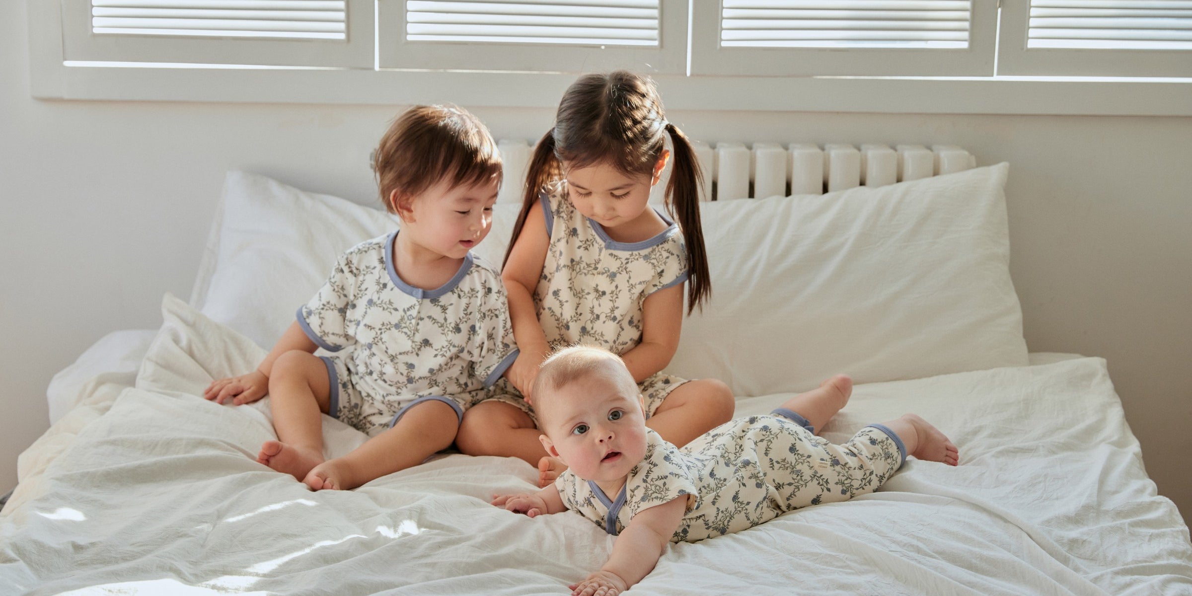 one toddler boy and his toddler sister are playing with a baby on the bed