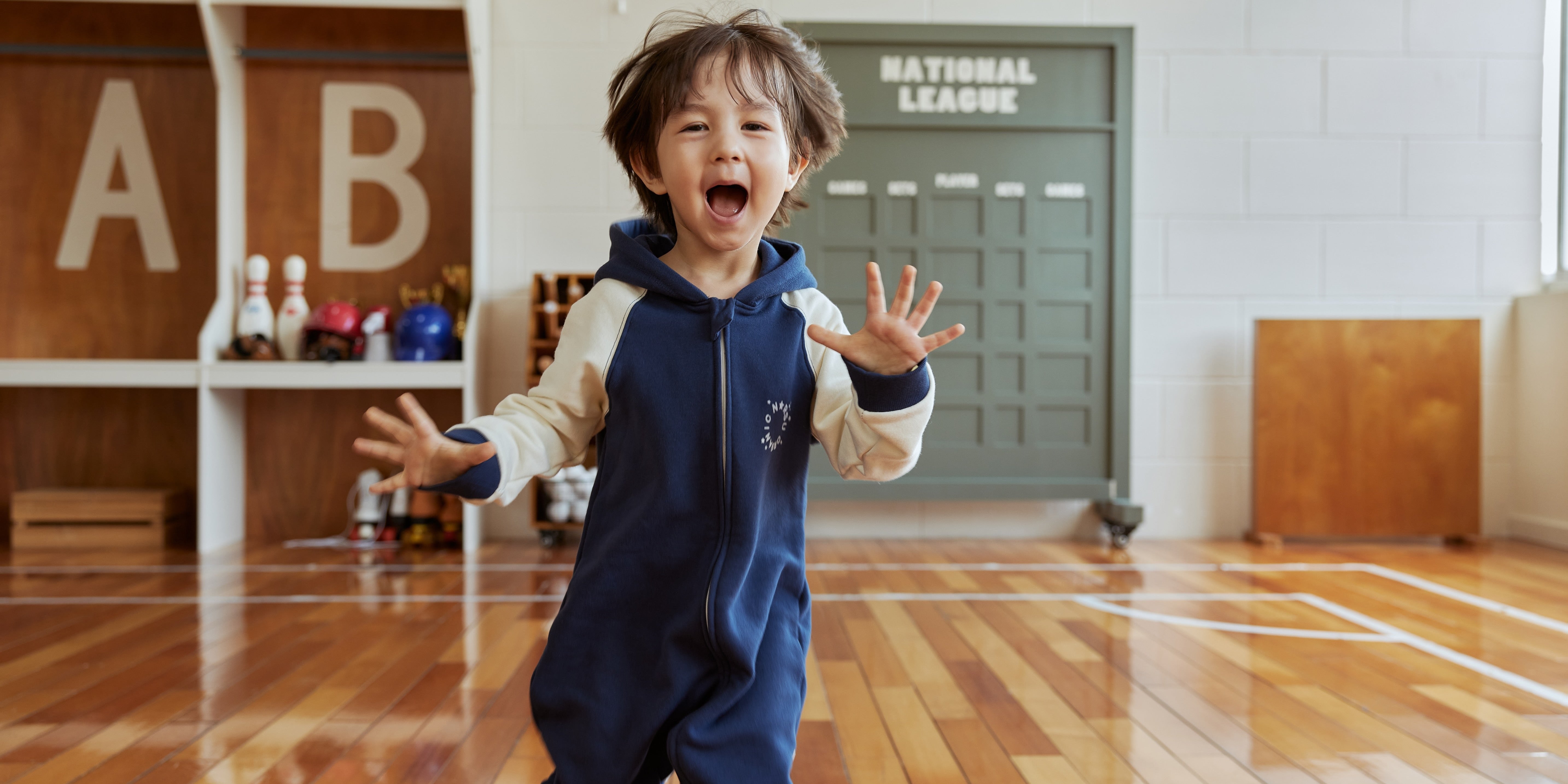 Child in navy outfit sitting on a beige rug with a blue blanket and white sofa in the background
