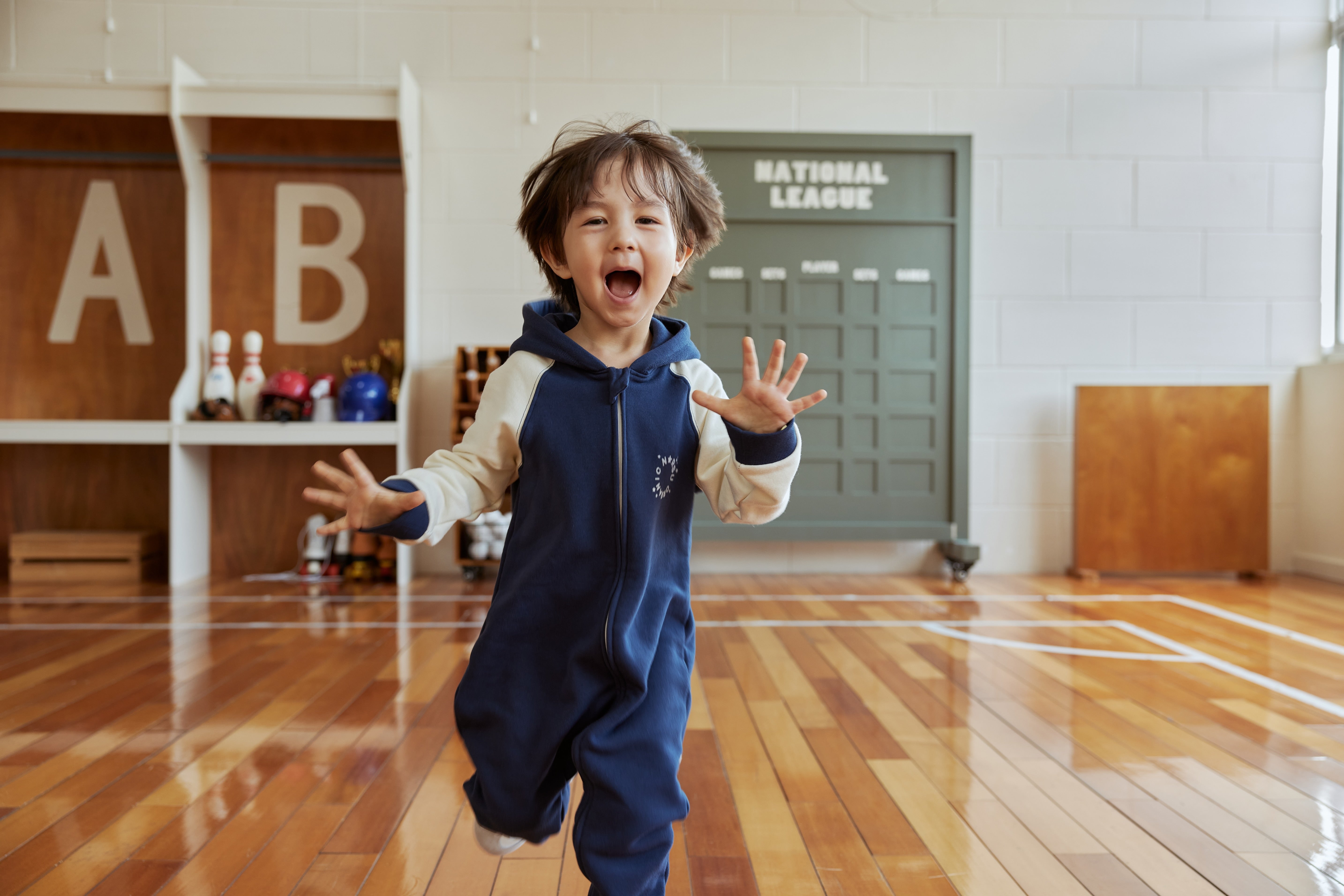 Child in navy outfit sitting on a beige rug with a blue blanket and white sofa in the background
