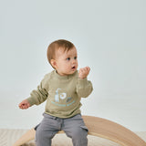 baby sitting on the chair and wearing Organic Toddler Cargo Fleece Sweatpants-Grey