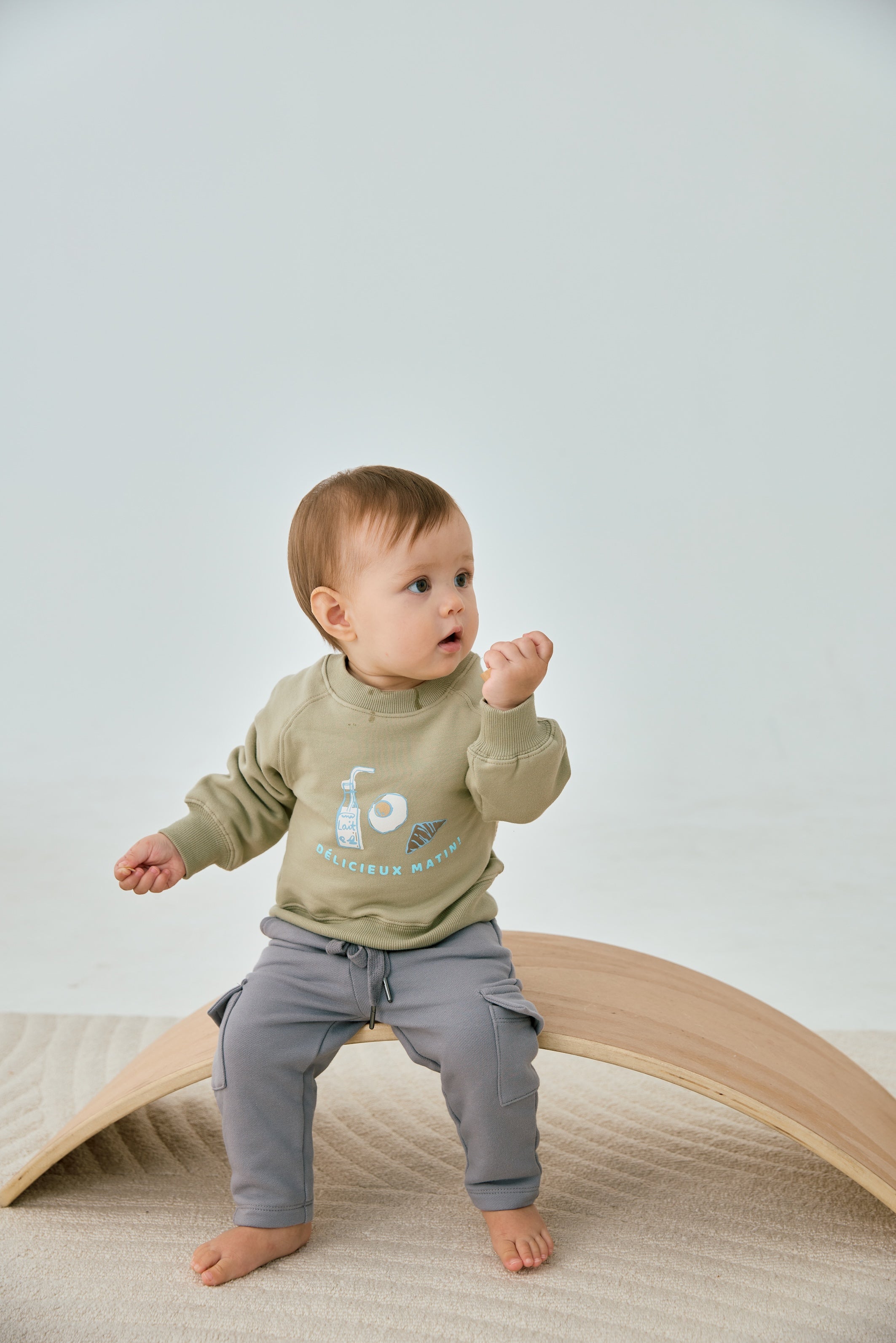 baby sitting on the chair and wearing Organic Toddler Cargo Fleece Sweatpants-Grey