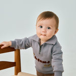 baby standing beside chair and wearing Toddler Organic Fleece Zip-up Sweatshirt-Dreams