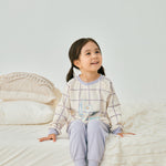 baby girl sitting on the bed and wearing Organic Toddler Pajama Set-Milky