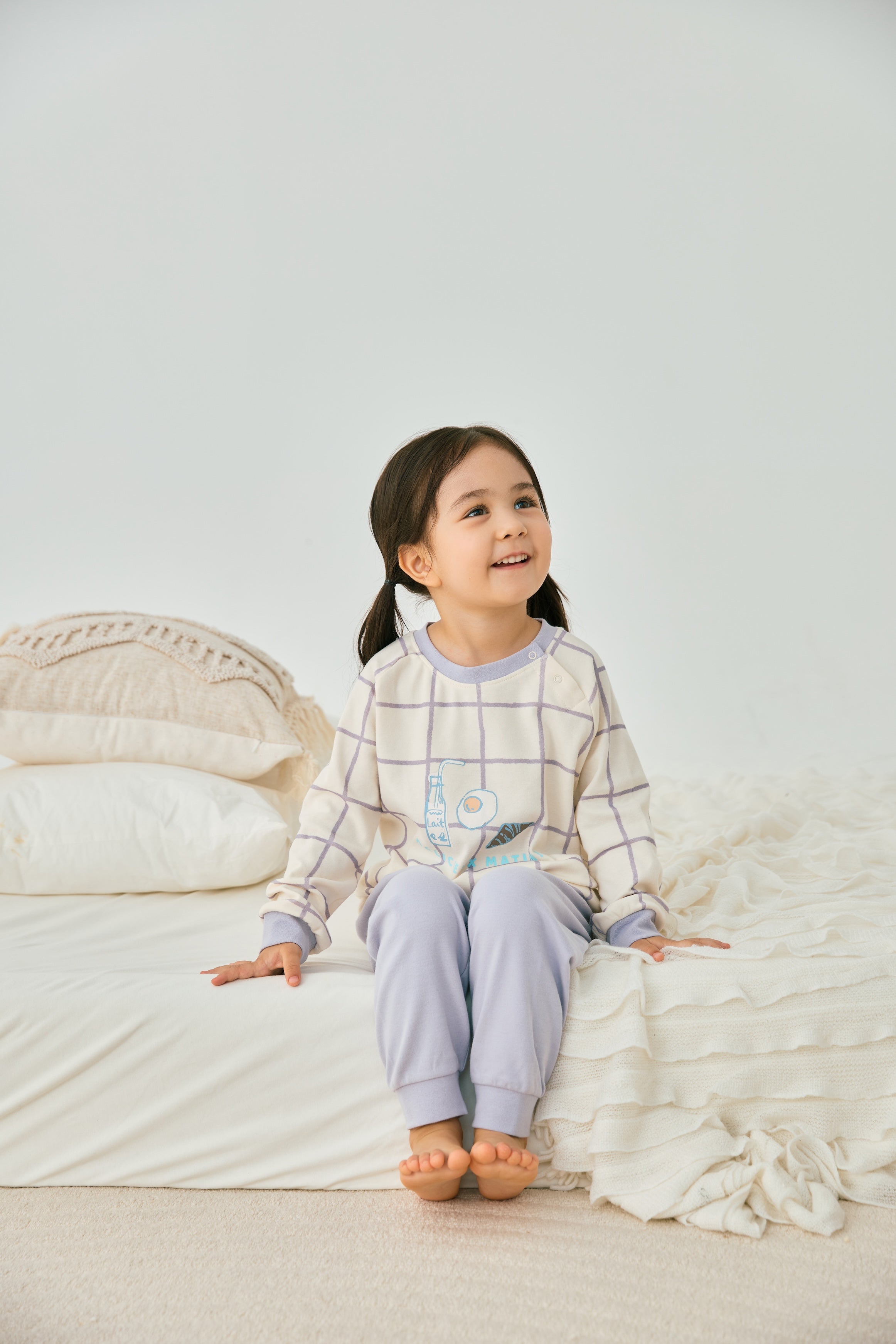 baby girl sitting on the bed and wearing Organic Toddler Pajama Set-Milky