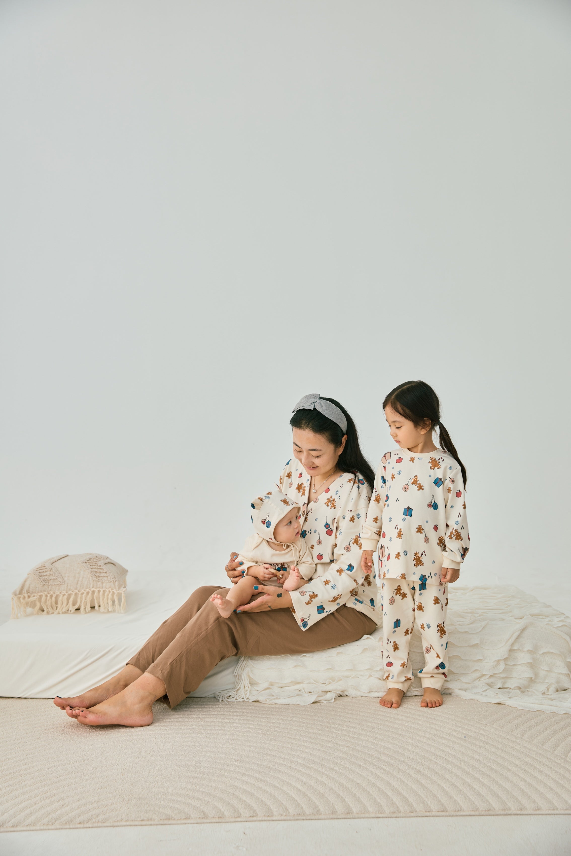 Mommy with 2 babies wearing norsu organic holiday special editon clothes and having fun on the bed