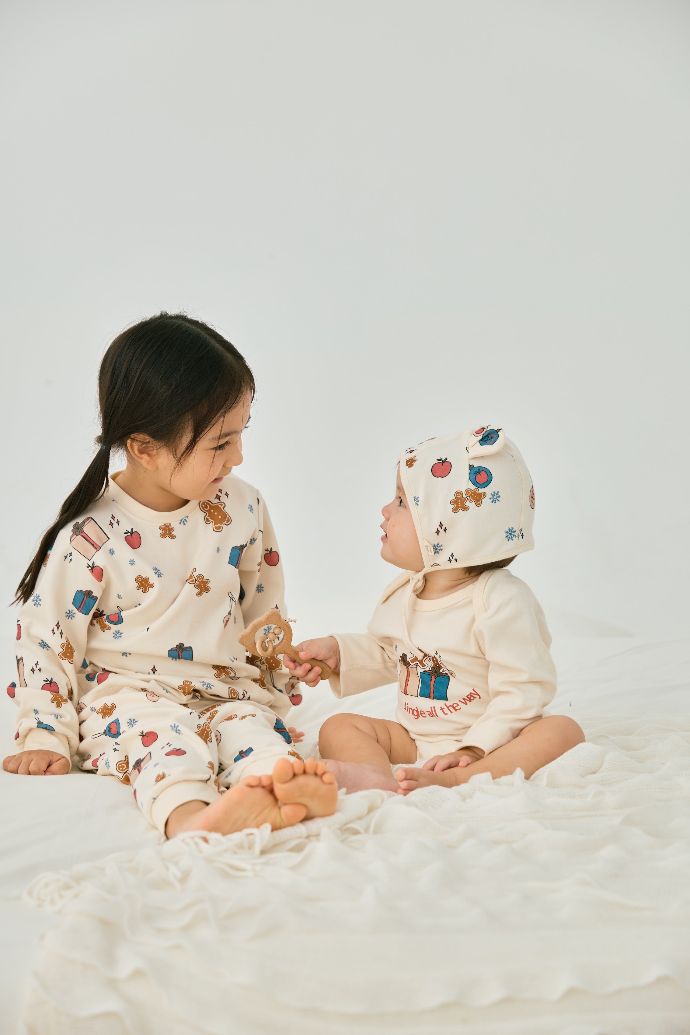 baby girl wearing Organic Toddler Pajama Set-Holiday Joy and watching a baby