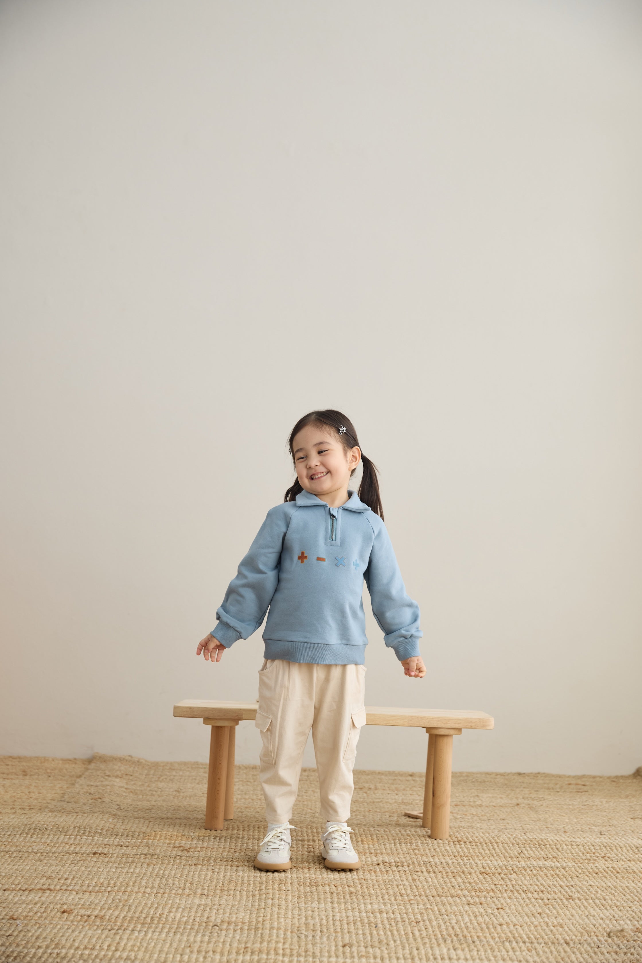 baby girl standing in front of a chair and wearing Toddler Organic Fleece Zip-up Sweatshirt-Symbols