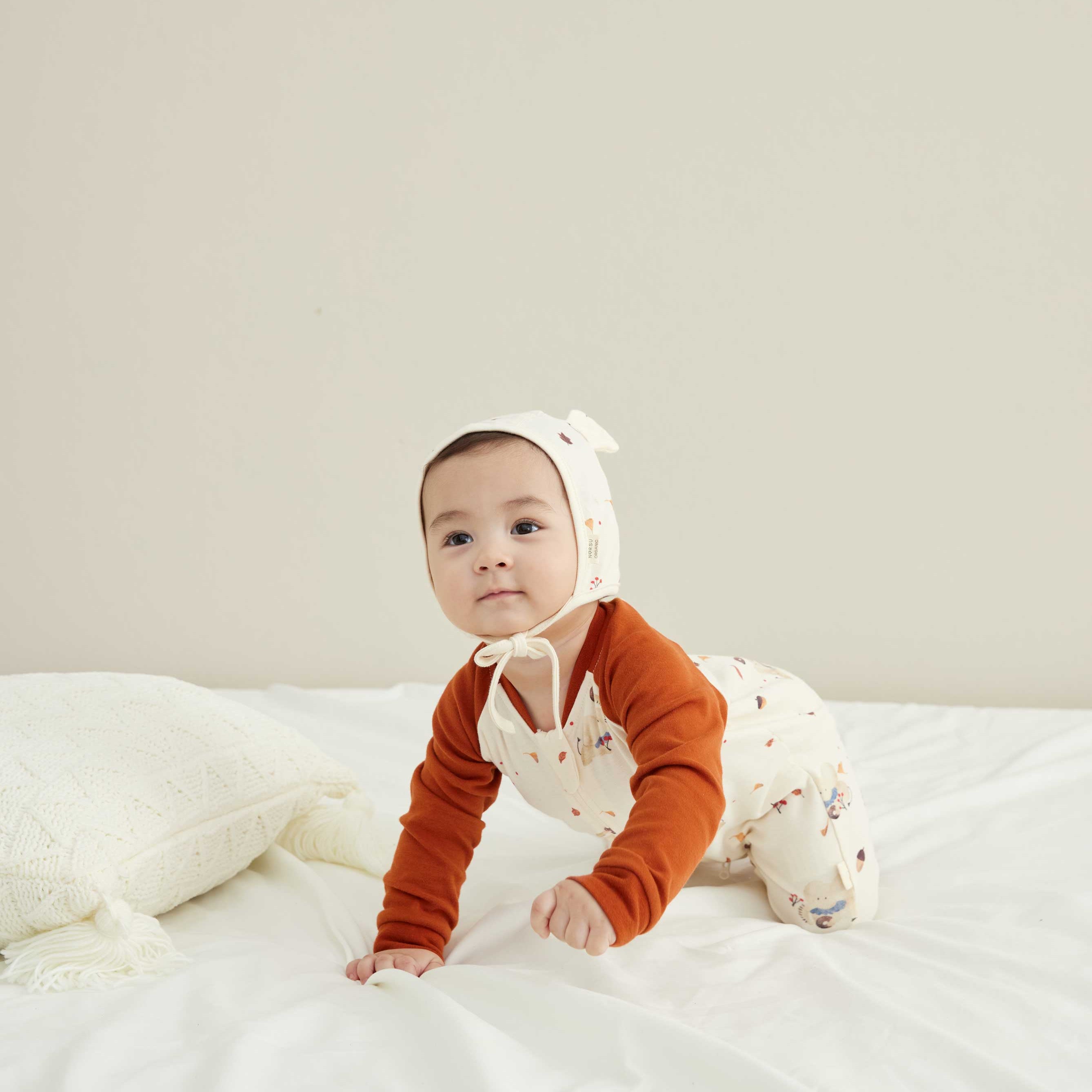 model wearing organic baby sleepers and bonnet hat 