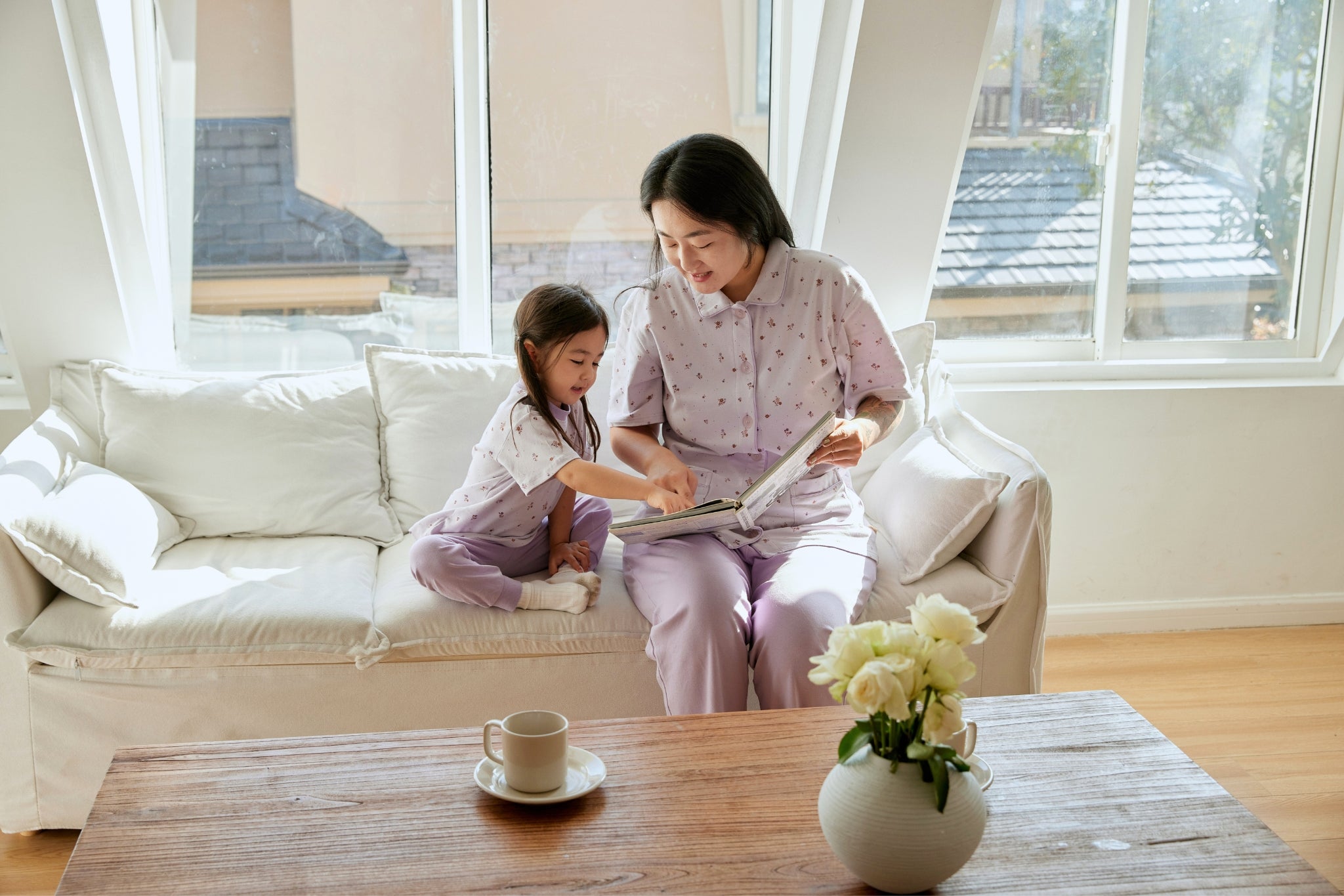 a toddler girl is readying book with her mom 