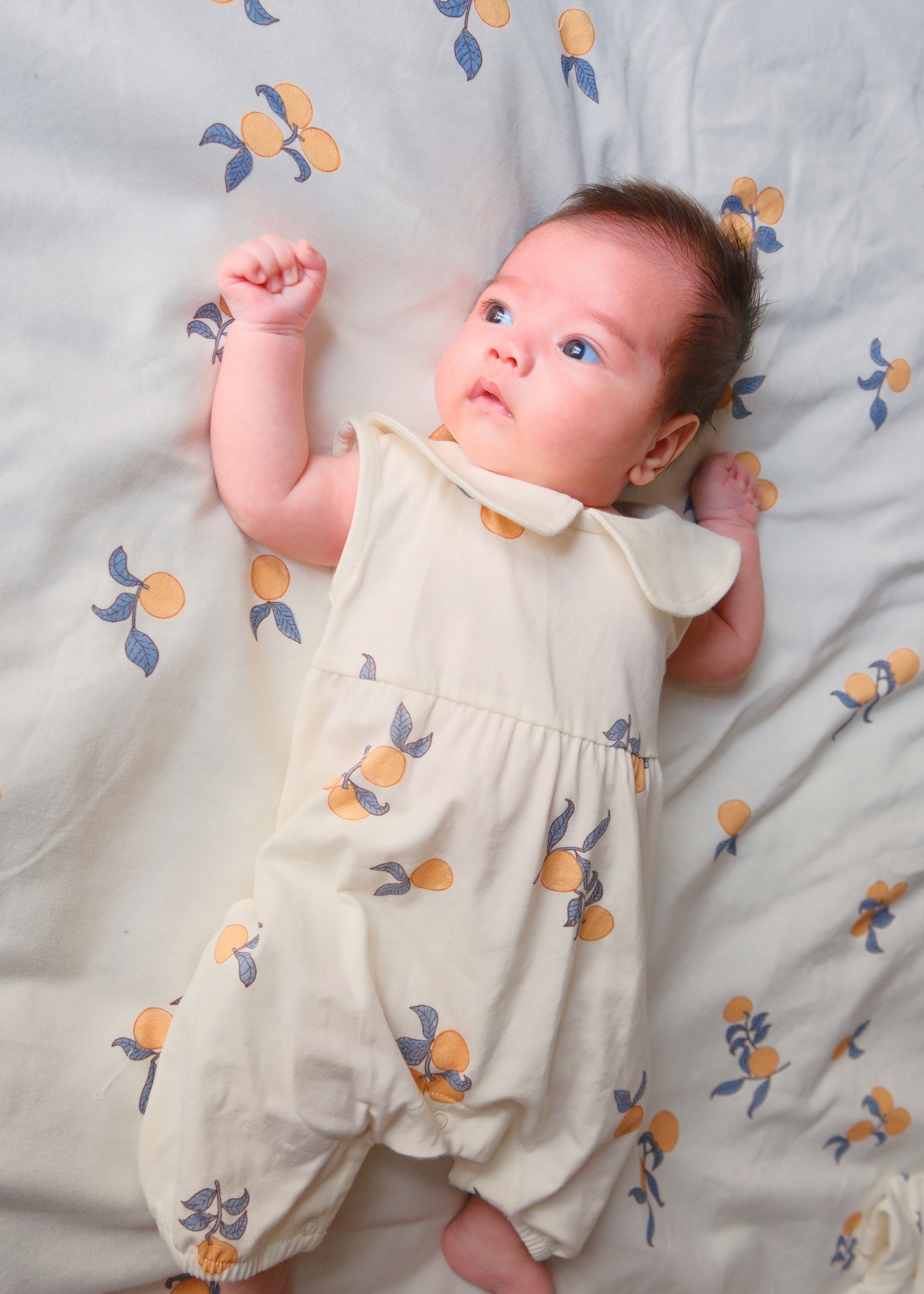 a baby boy is lying on the bed and wearing Baby Collar Tank Romper-Clementine 