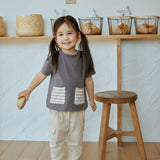 baby girl stand beside a chair , hold a bread and smiling at you