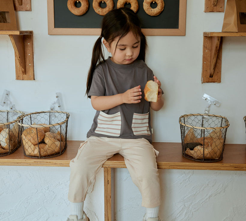 baby girl sitting on the table and hold a bread