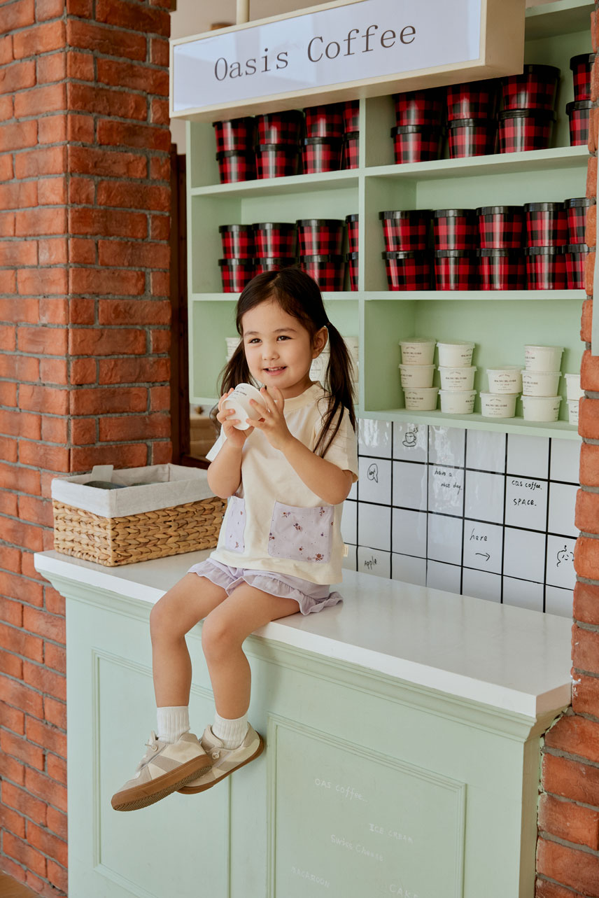 baby girl sitting on the table and holding a icecream cup