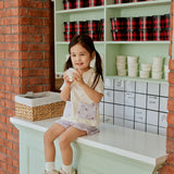 baby girl sitting on the table and holding a icecream cup