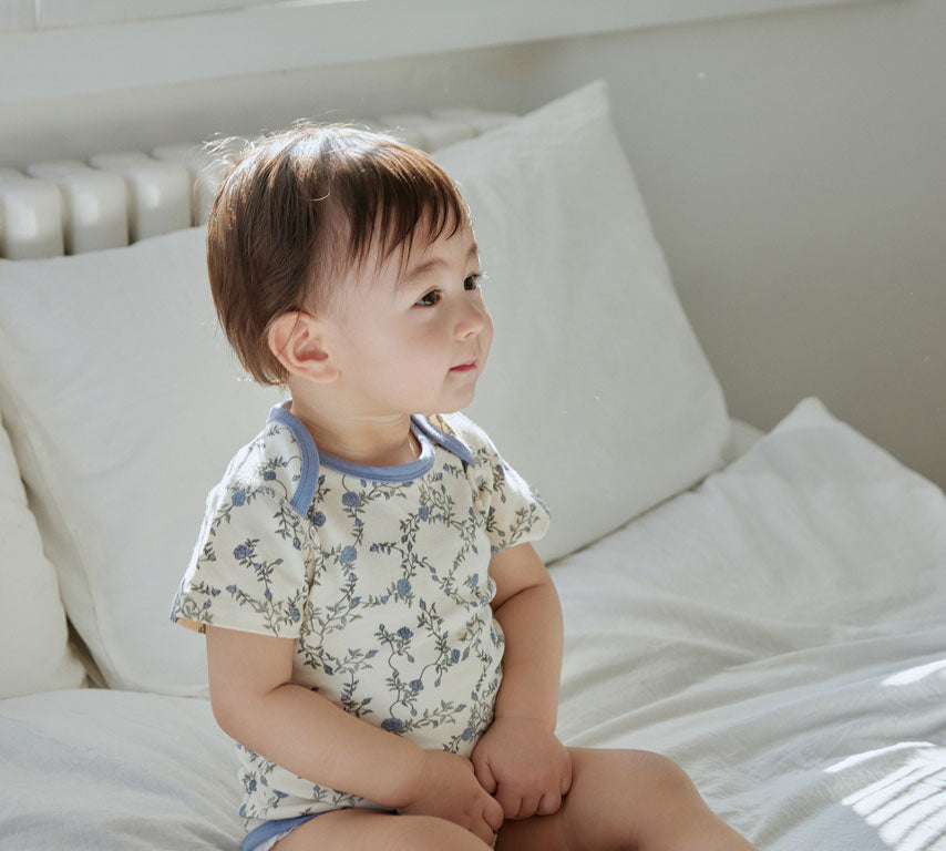 baby sitting on the bed and wearing Baby Organic Short-Sleeve Onesie-Roses