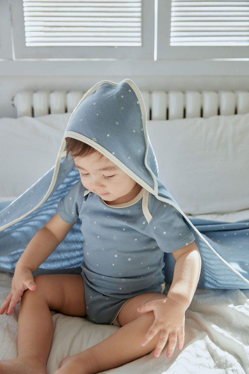 baby boy is wearing Baby Organic Short-Sleeve Onesie-Blue Starry and wearing blanket as well