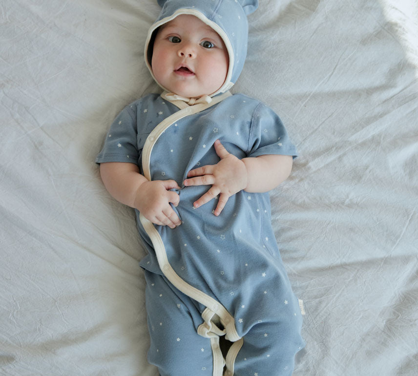 baby boy laying on the bed and wearing Baby Organic Kimono Sleeper-Blue Starry
