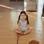 baby sitting on the floor and leash a dog