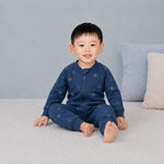 Child wearing a blue bodysuit with hockey patterns on a gray couch.