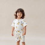 Child wearing a lemon romper with colorful patterns on a beige background