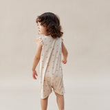 Child wearing a light-colored dress with a subtle pattern on a plain background