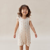 Child wearing a light-colored dress with a subtle pattern on a plain background