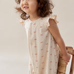 Child wearing a white dress with small patterns, holding a woven basket against a plain background