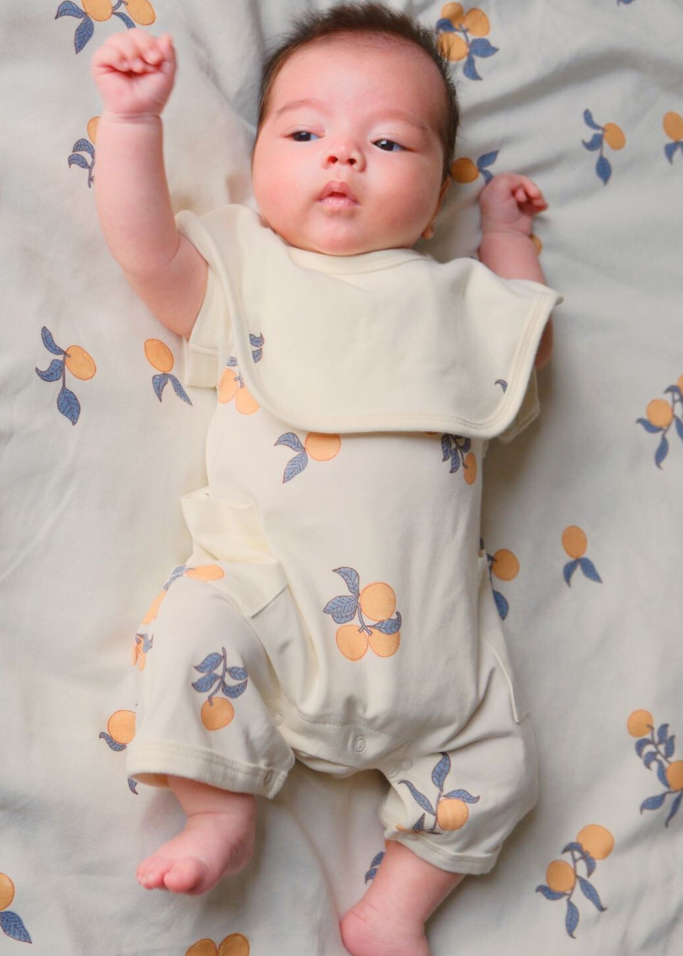 3. Adorable baby in Clementine onesie, complemented by soft organic cotton bibs for a cozy vibe.

