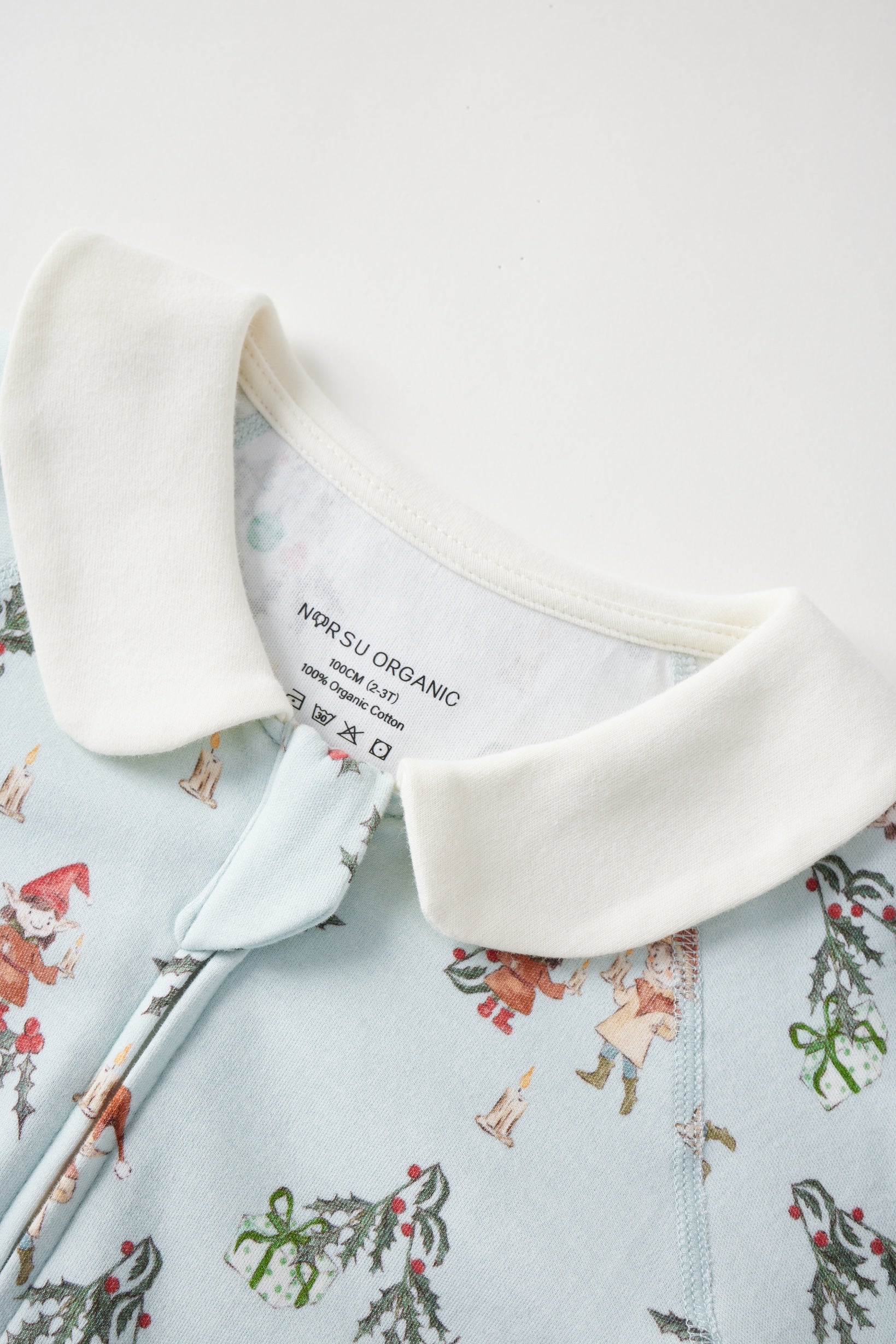 Close-up of a baby outfit with jolly pattern and white collar, featuring a visible brand label.