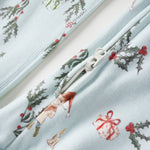 Close-up of a fabric with Christmas-themed designs including holly leaves, ribbons, and a snowman on a light blue background.