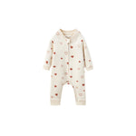 A long-sleeve baby romper in cream with a pattern of small red and pink hearts, featuring a front zipper and snap closure.
