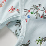 Close-up of a baby sleeper with Christmas-themed print on a light blue background