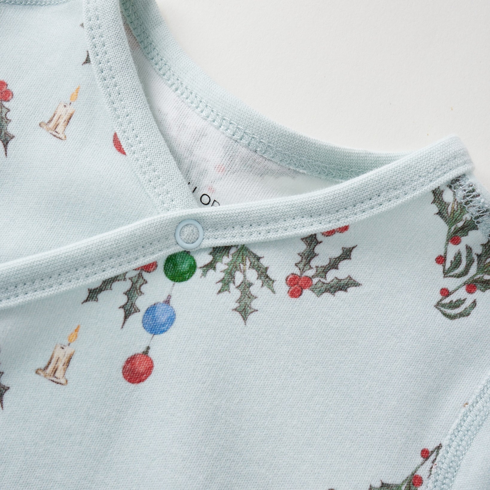Light blue baby sleeper with Christmas-themed pattern on a white background