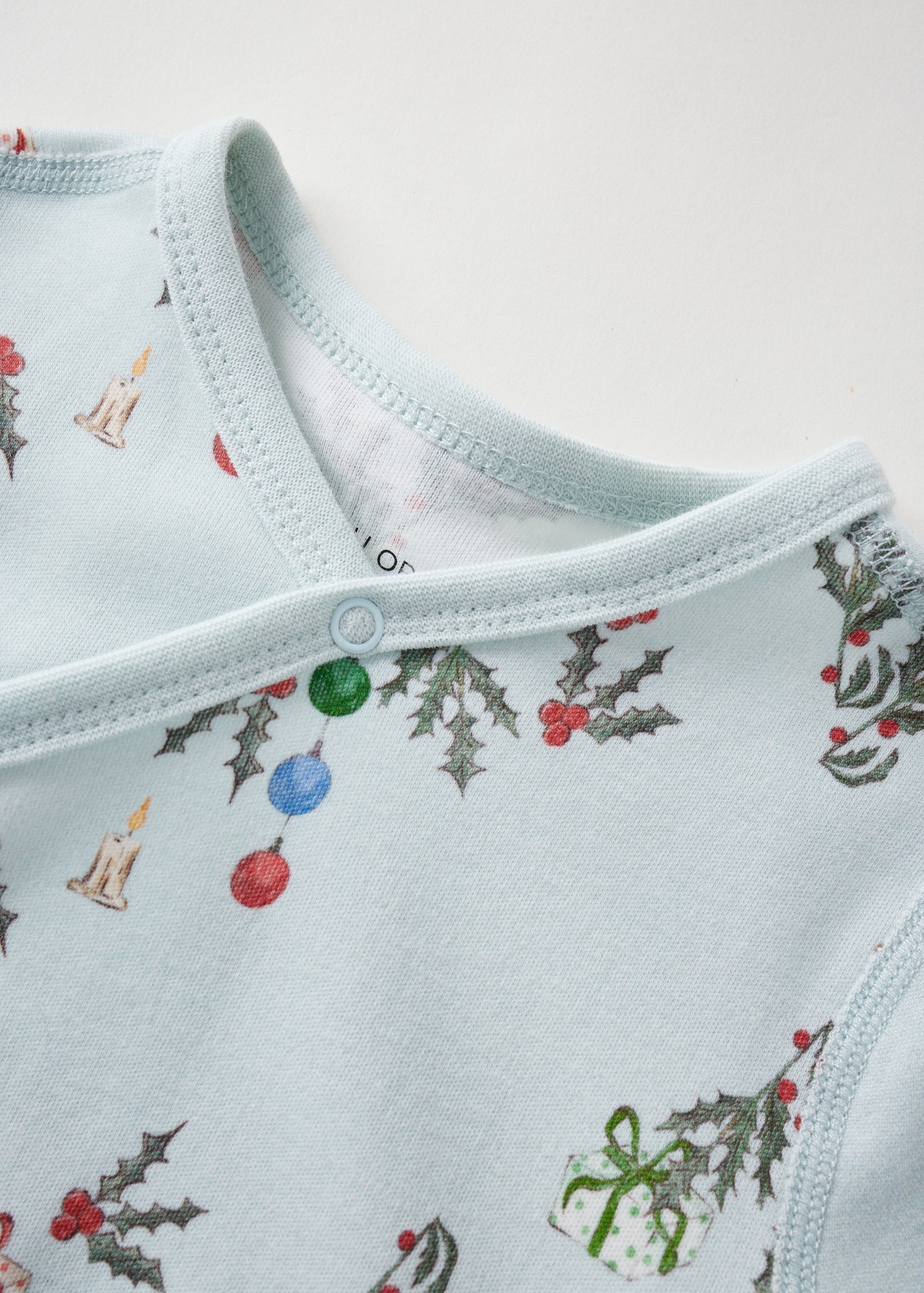 Light blue baby sleeper with Christmas-themed pattern on a white background