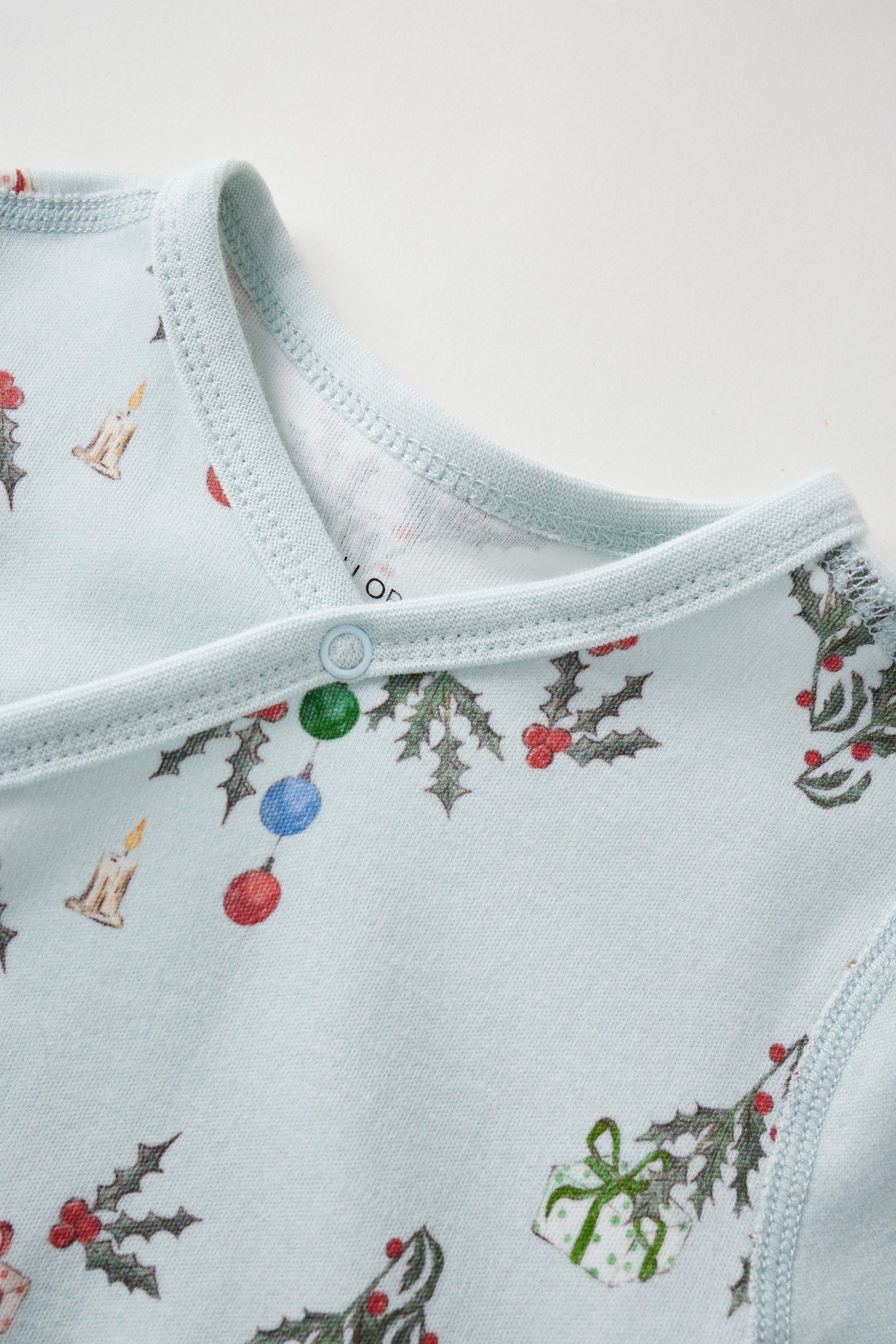 Light blue baby sleeper with Christmas-themed pattern on a white background
