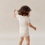 Child wearing a white onesie with small patterns on a plain background