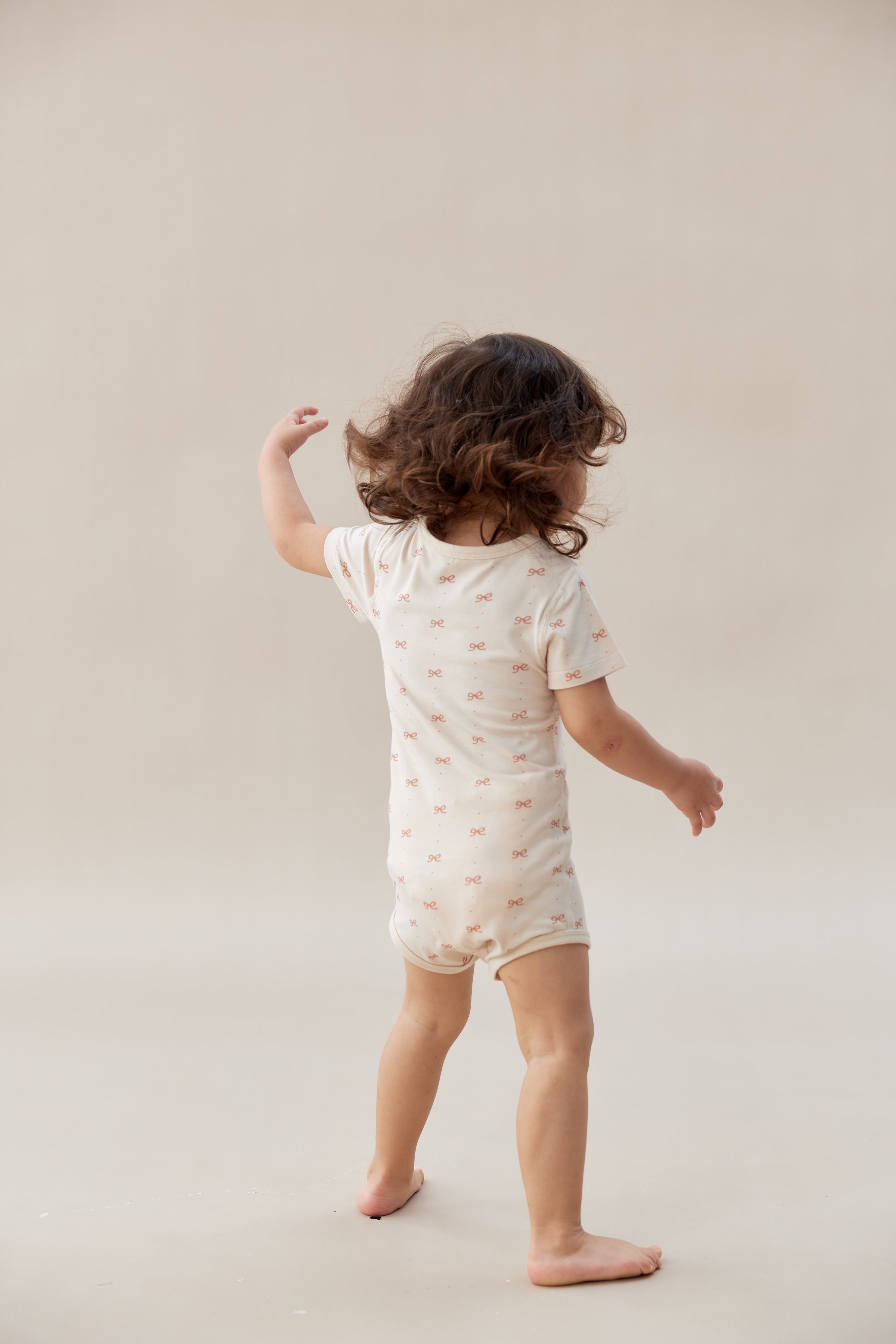Child wearing a white onesie with small patterns on a plain background
