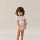 Child wearing a beige organic cotton onesie with a subtle pattern on a plain background