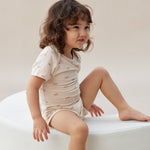 Child sitting on a white cushion against a plain background