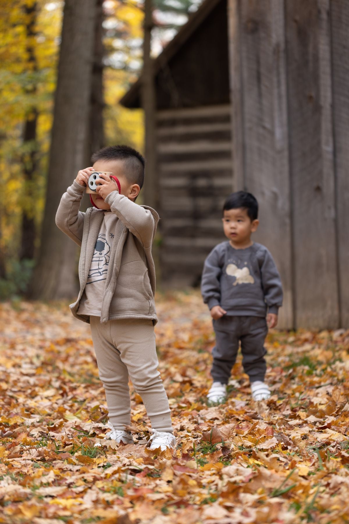 1 baby boy hold his camera and taking picture another one is watching at him