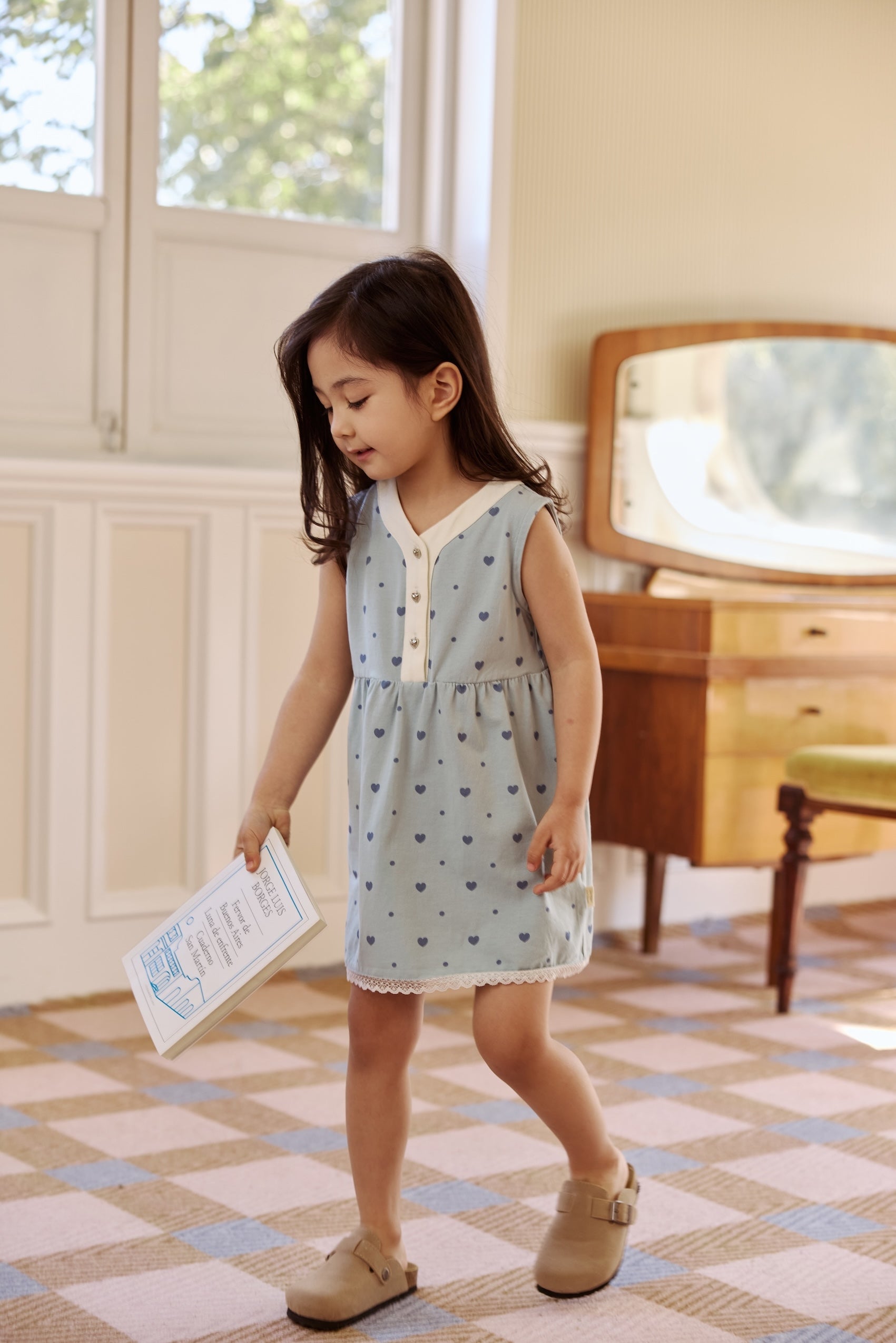 Toddler girl wearing a light blue heart print summer dress indoors