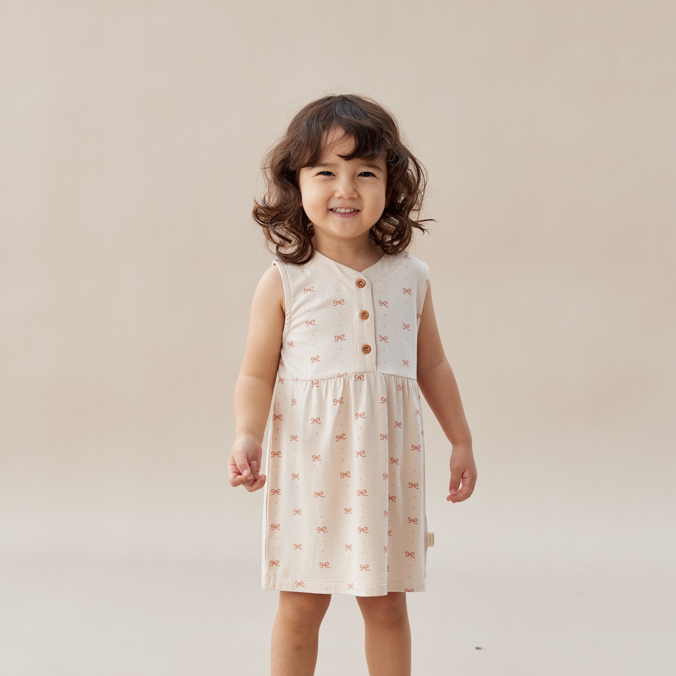 Young child wearing a patterned dress on a plain background