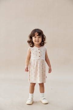 Young child wearing a patterned dress on a plain background