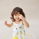 Child playing with lemons in a glass bowl on a light background