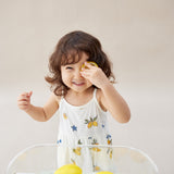 Child playing with lemons in a glass bowl on a light background
