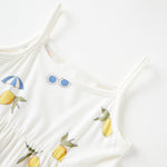White dress with lemon and umbrella patterns on a white background