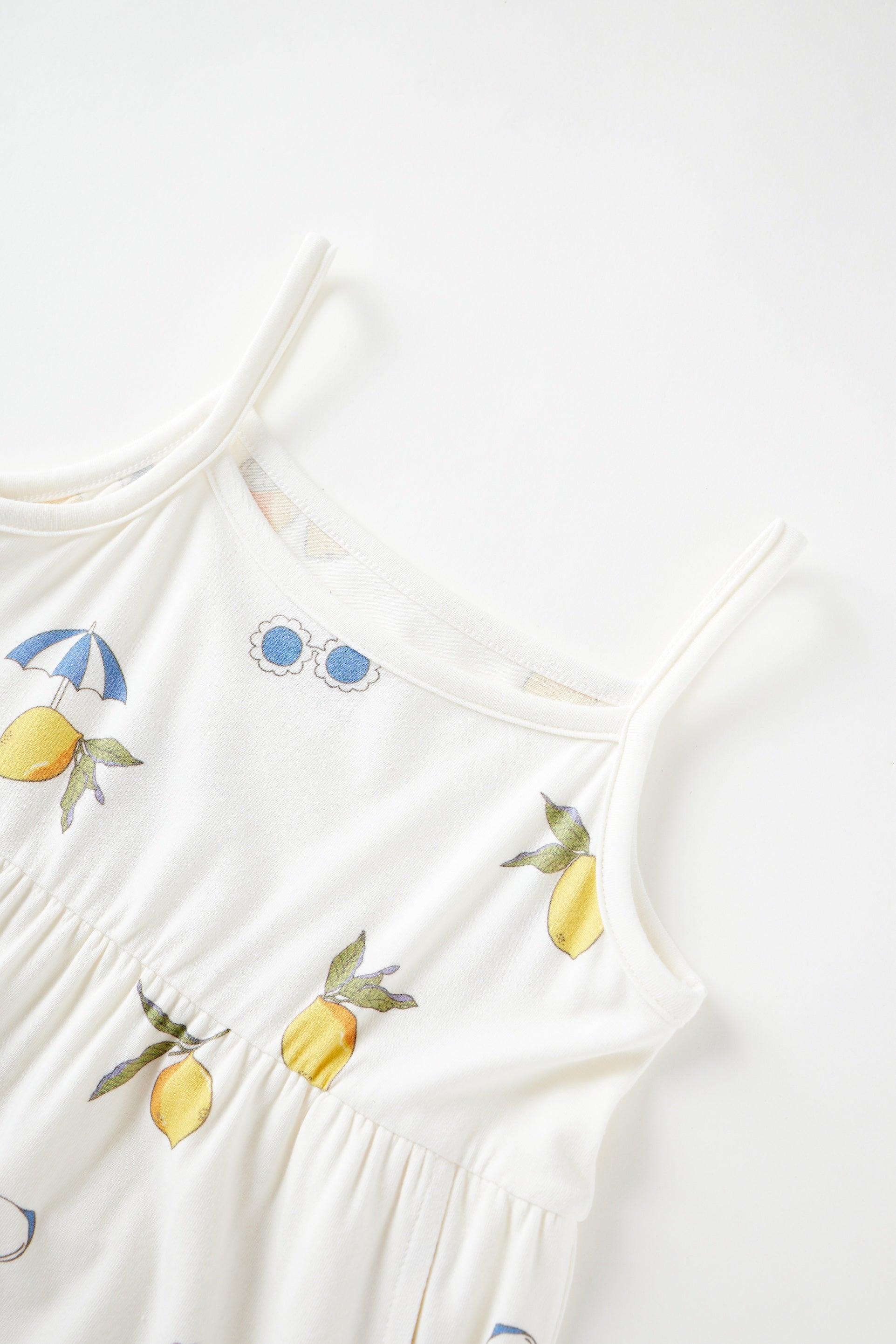 White dress with lemon and umbrella patterns on a white background